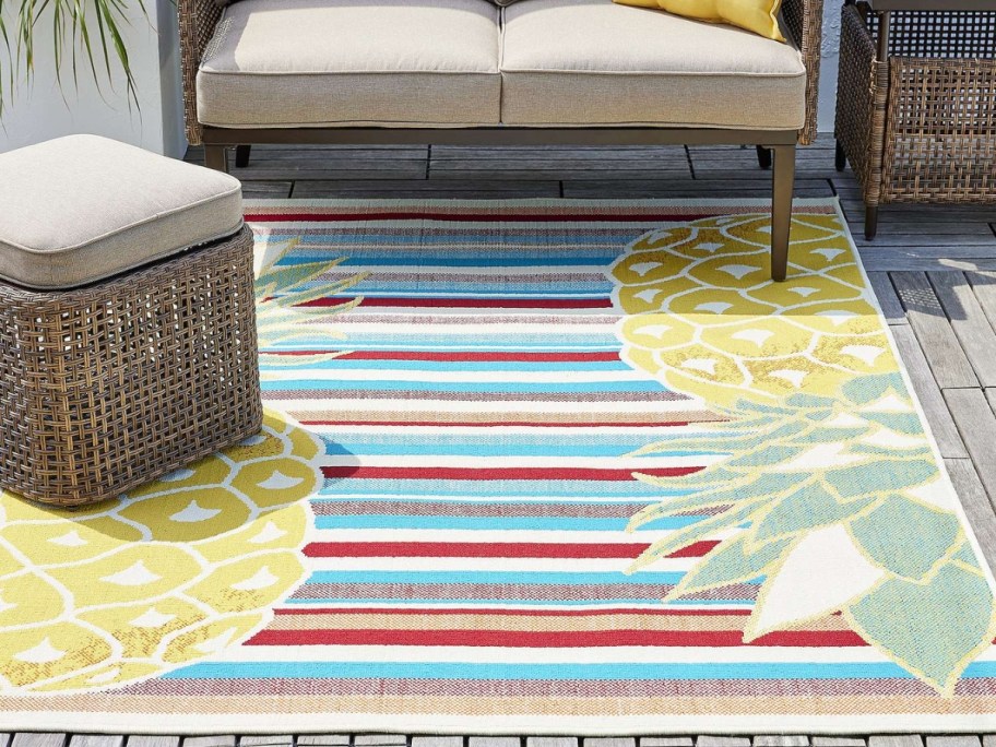 outdoor space with colorful stripes and pinapple print rug and tan wicker furniture