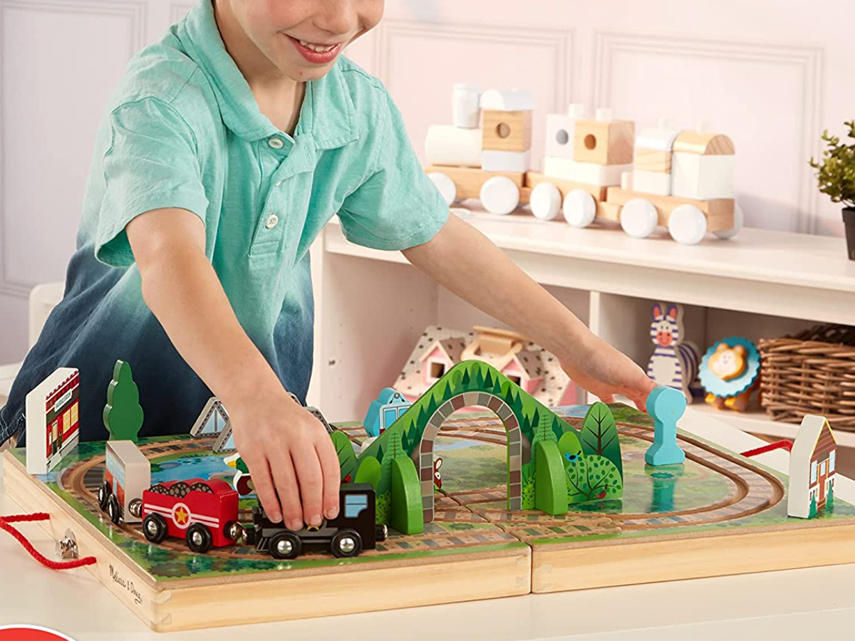 boy playing with a melissa & doug take along railroad train toy playset