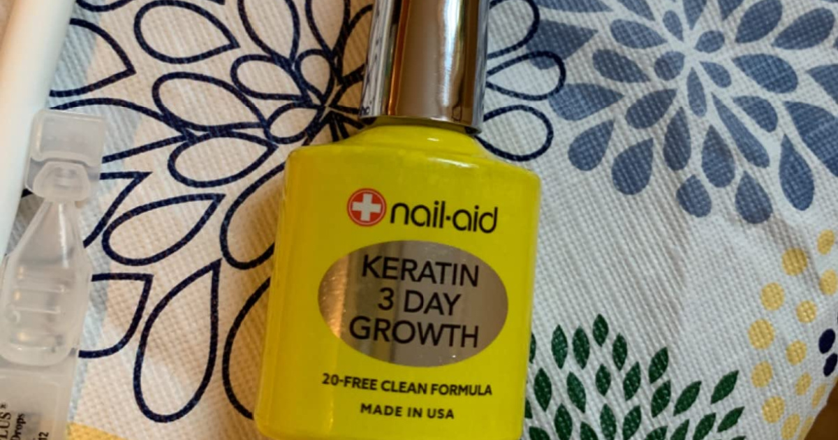 bottle of nail aid keratin laying against a patterned cloth background