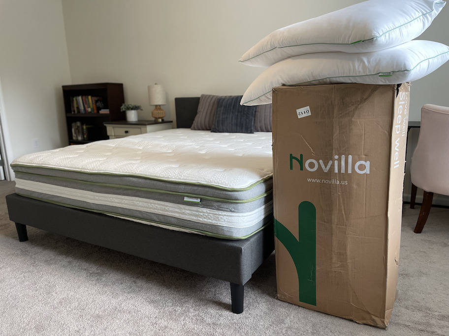 novilla mattress with boxes and pillows stacked on floor next to it
