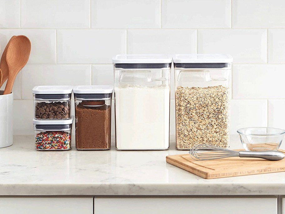 food containers with oatmeal, flour and more in them on countertop 