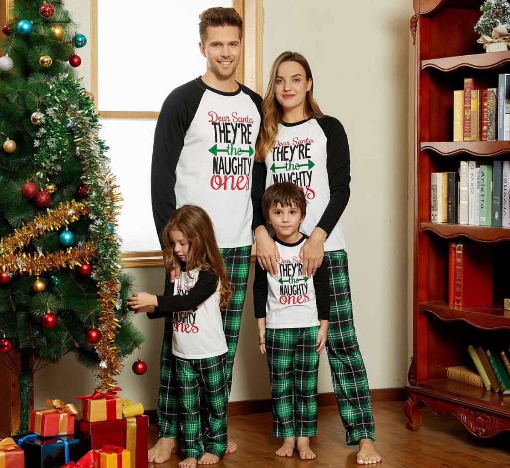 family wearing matching pajamas near tree