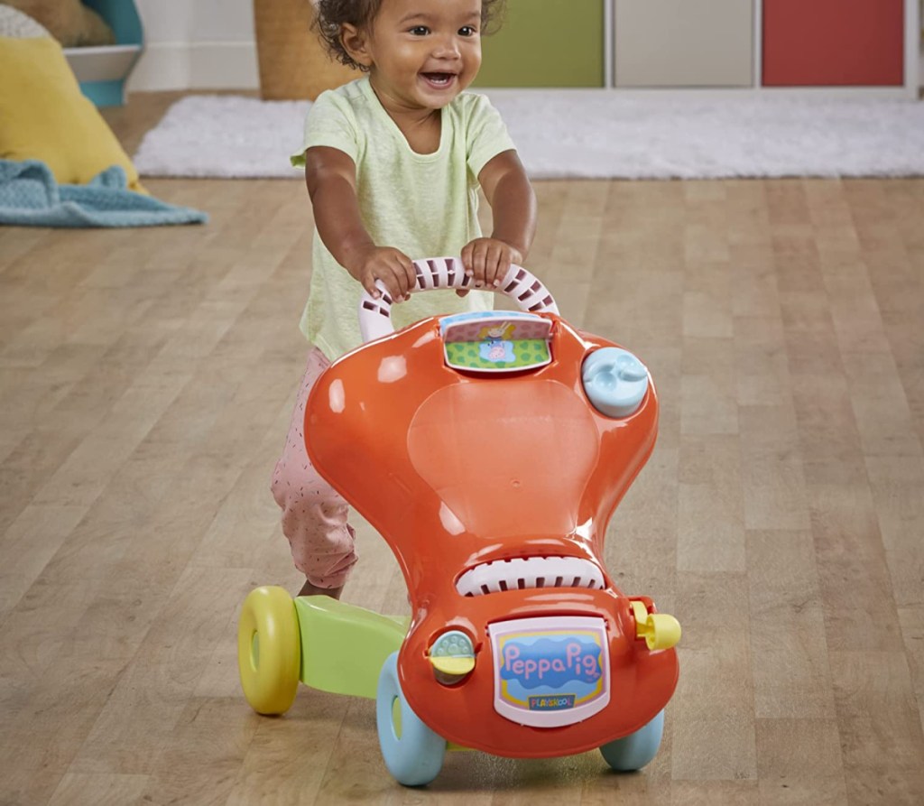 girl pushing a peppa pig playskool ride on toy and walker