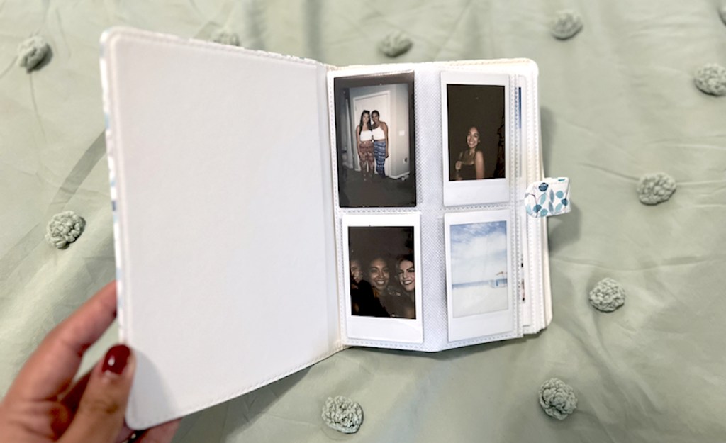 hand holding polaroid album with photos inside