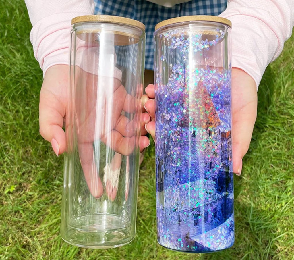 hands holding clear and snow globe glass tumblers 