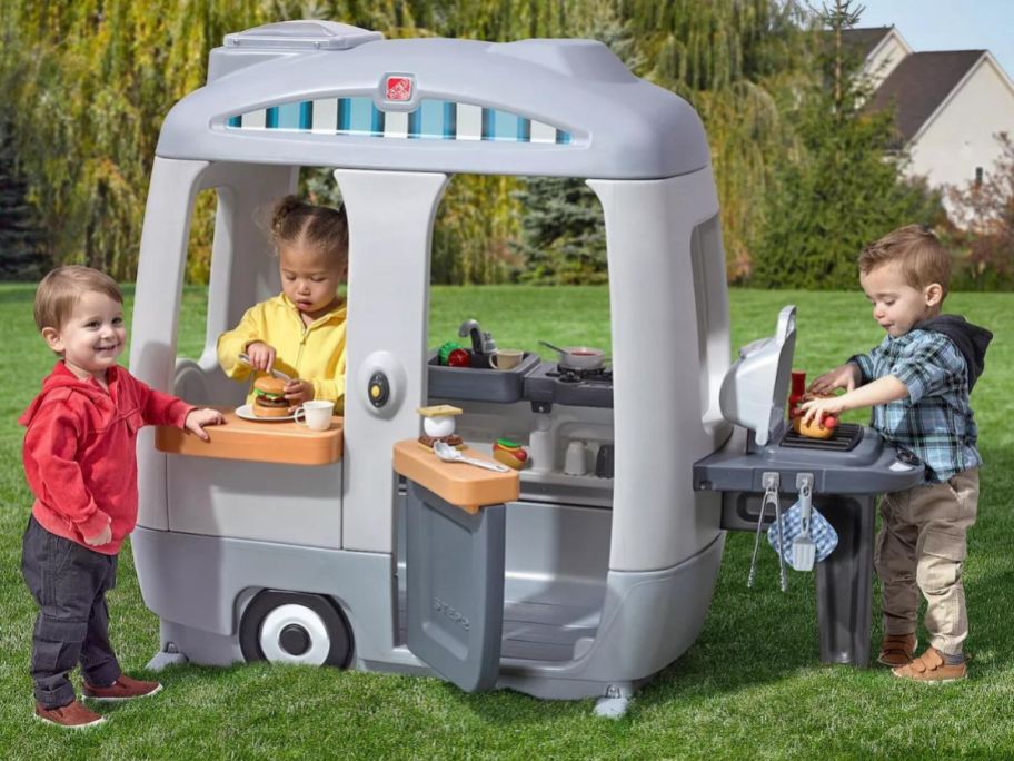kids playing with step2 adventure camper in yard