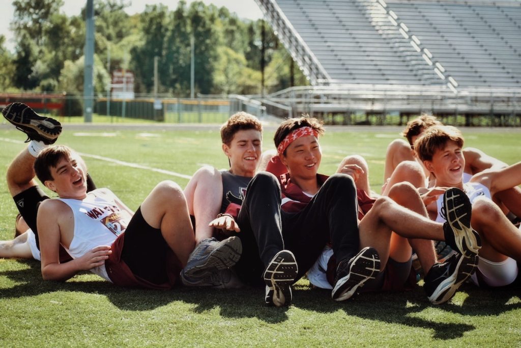teen boys laying n grass outside on football field