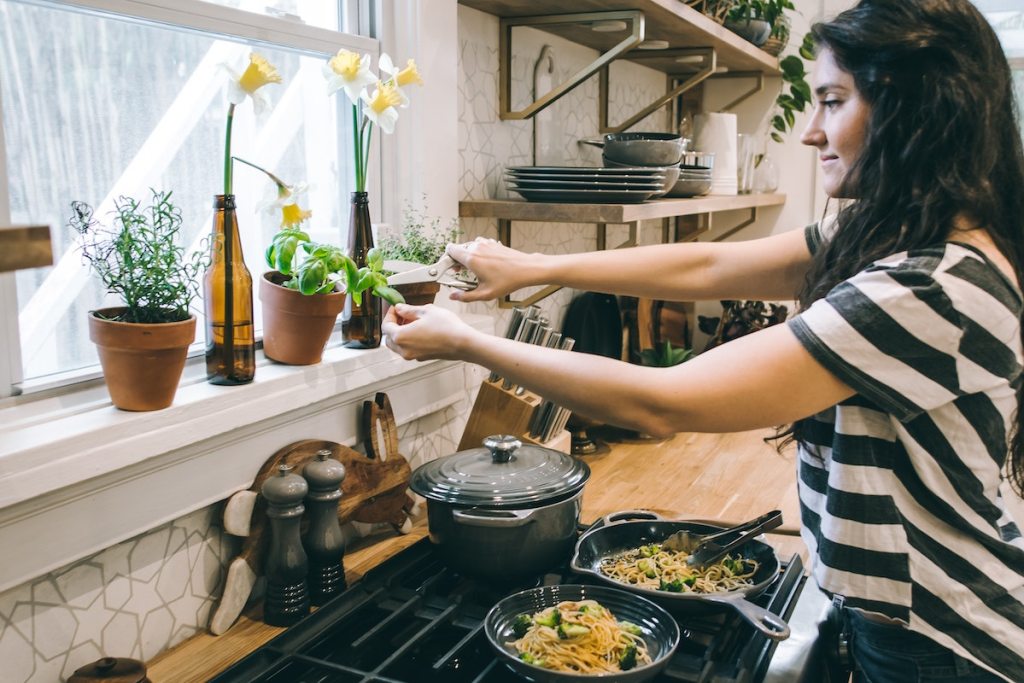 girl standing in kitchen cutting herbs with scissors