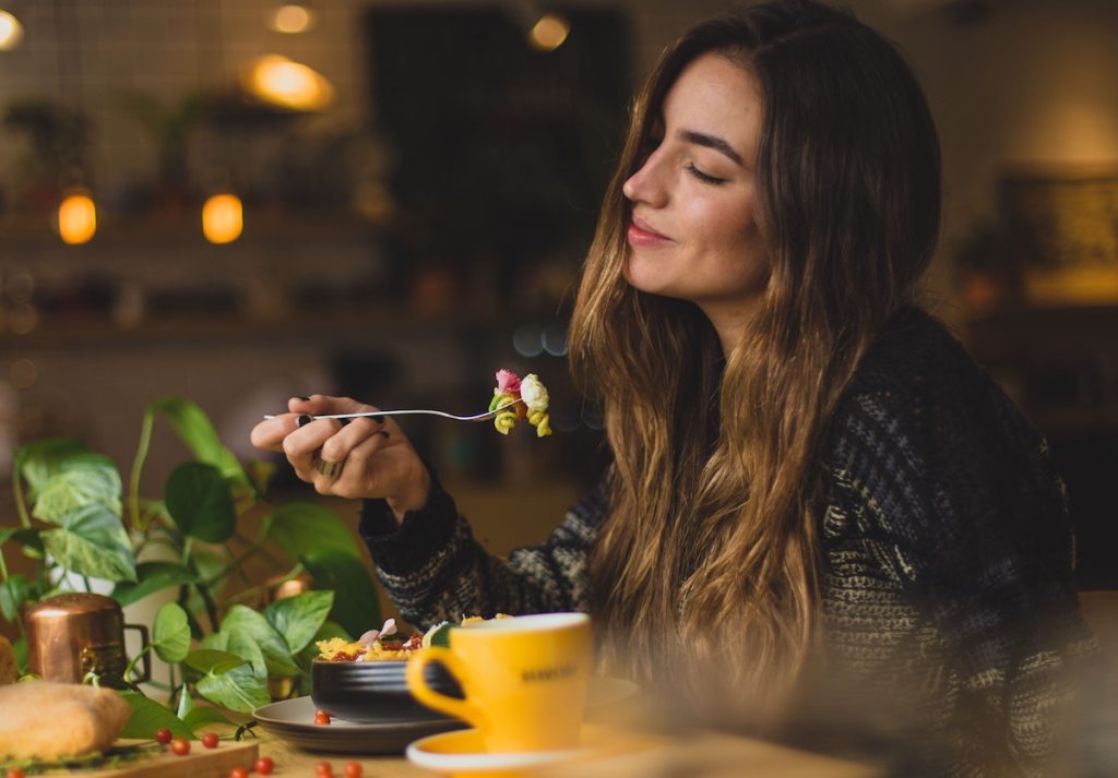 teen girl smiling with eyes closed sitting at table eating food