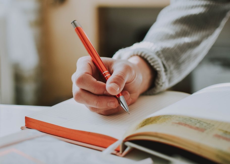 person hand writing in journal