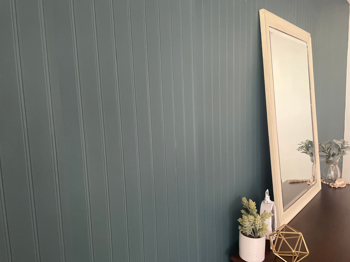bluish green vintage wallpaper with vertical slats and mirror against wall