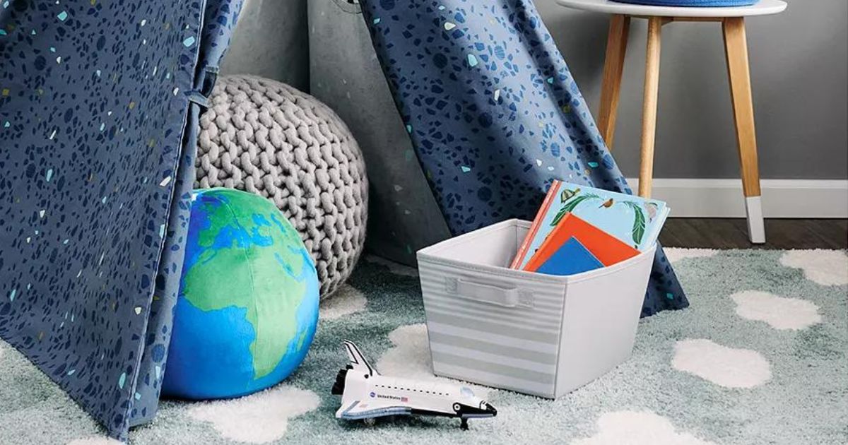 gray and white striped storage bin holding books near play tent in room