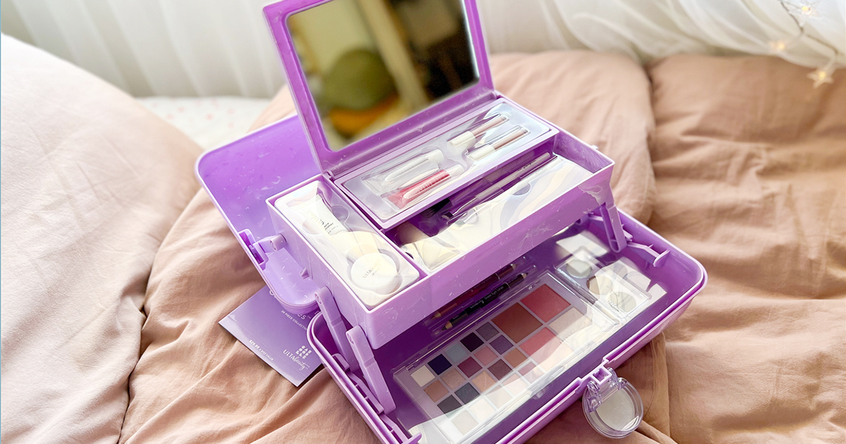 ulta Caboodles beauty box filled with makeup and cosmetics tools on bed