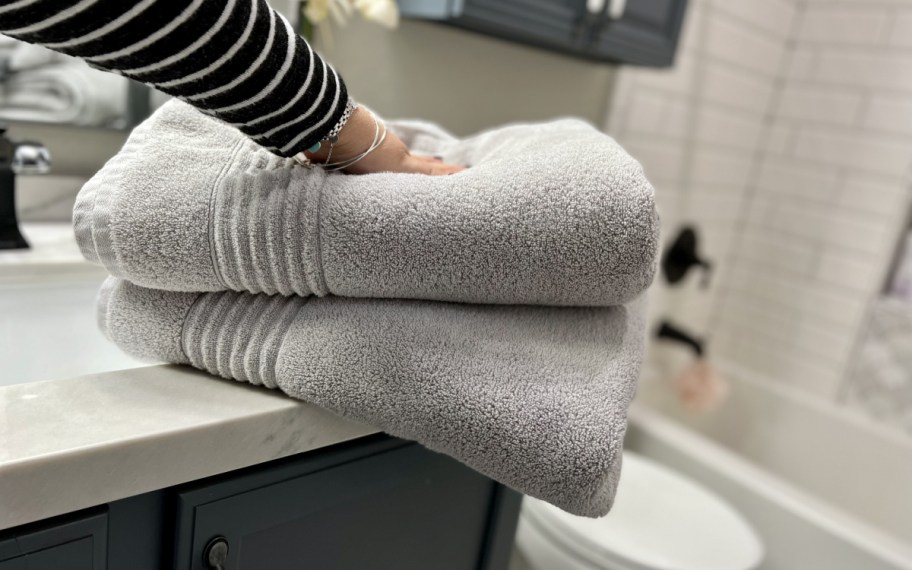 hand touching two stacked grey vera wang towels