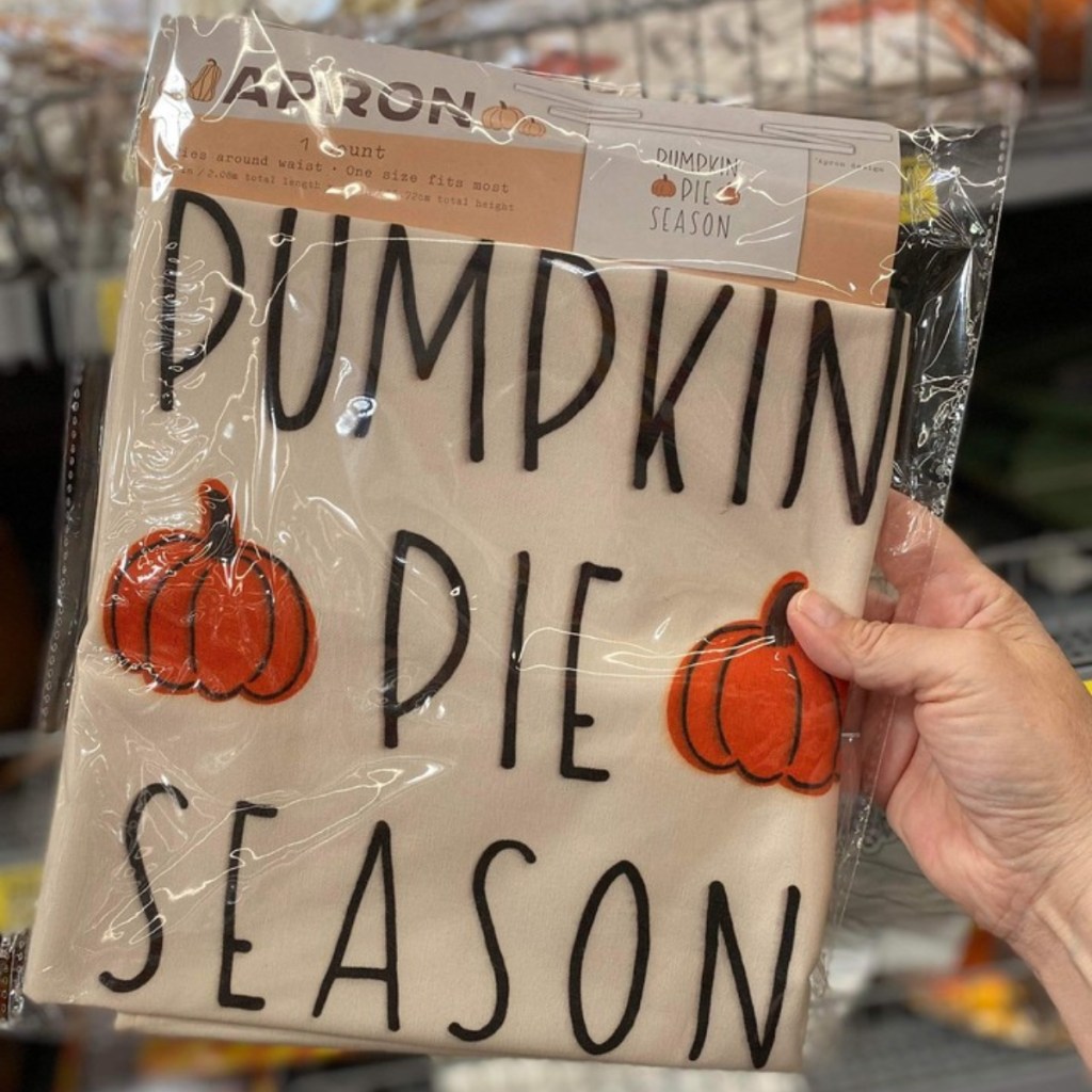 holding an apron reading "pumpkin pie season"