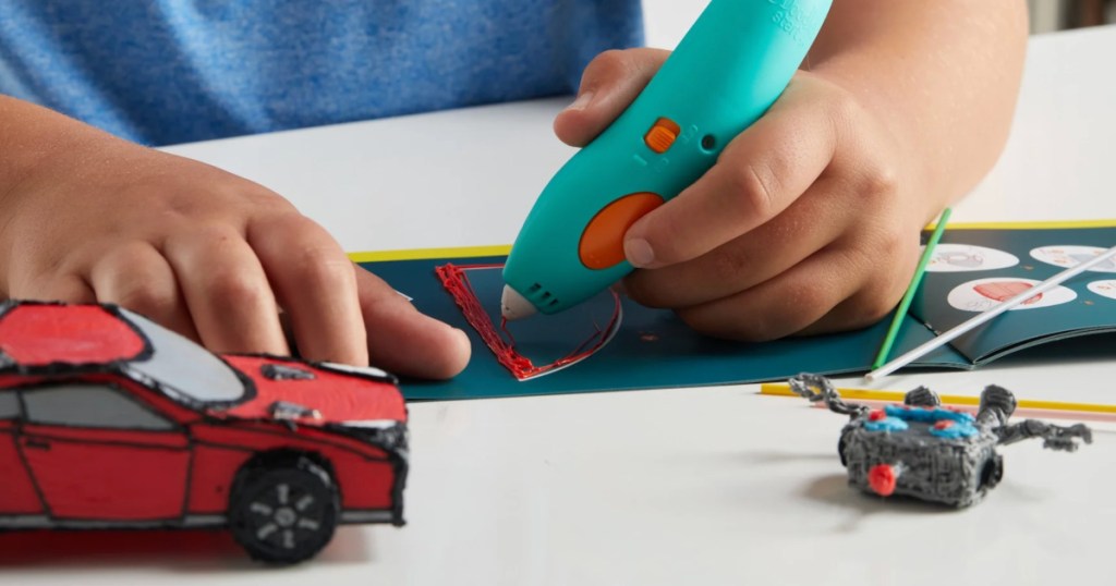 Toddler coloring with 3-D pen on pad