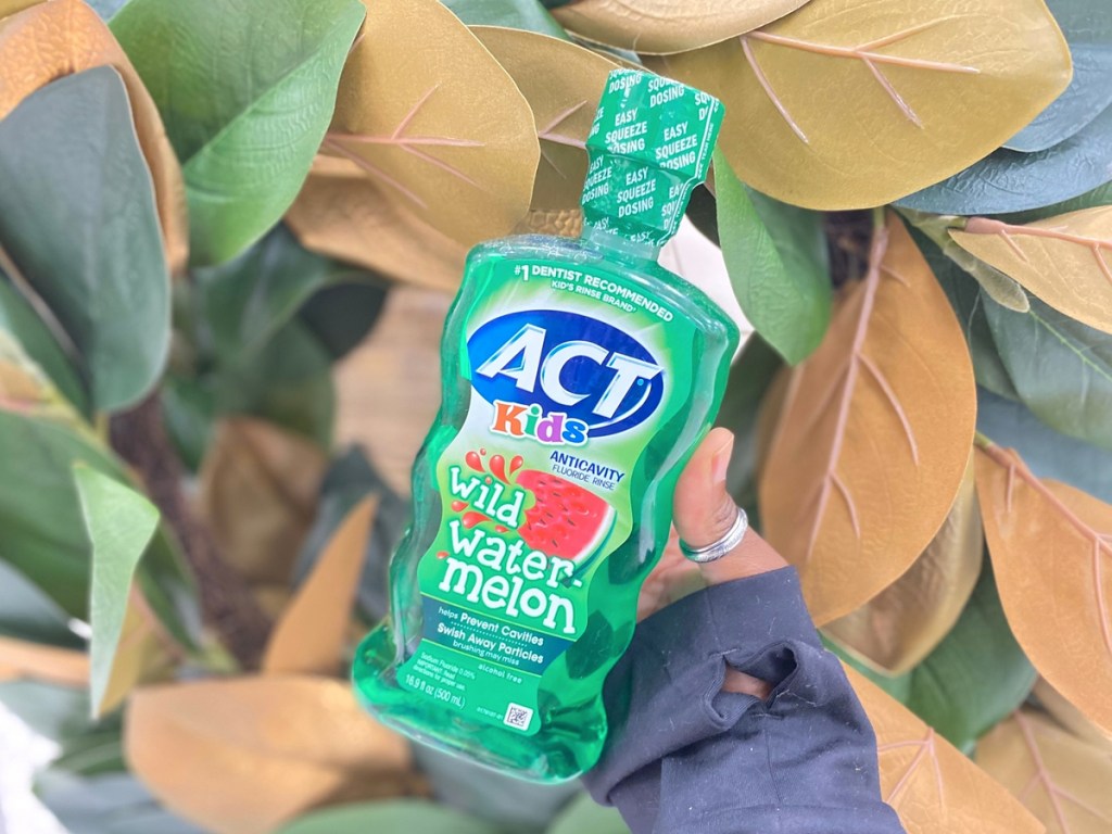 hand holding green bottle of act kids mouthwash in watermelon flavor