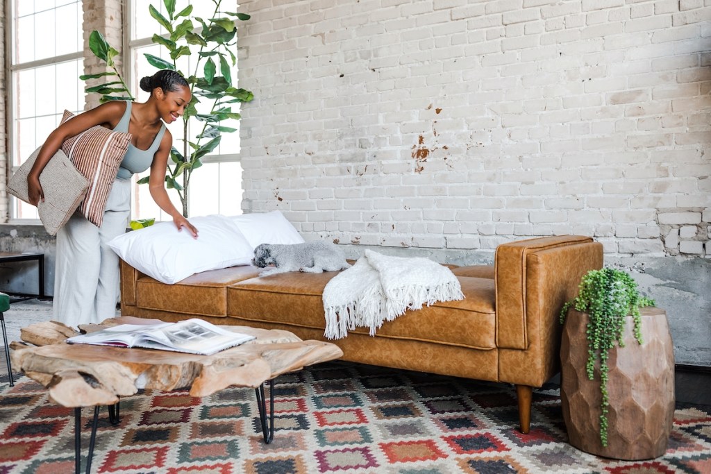 woman making bed with pillows on vegan leather couch