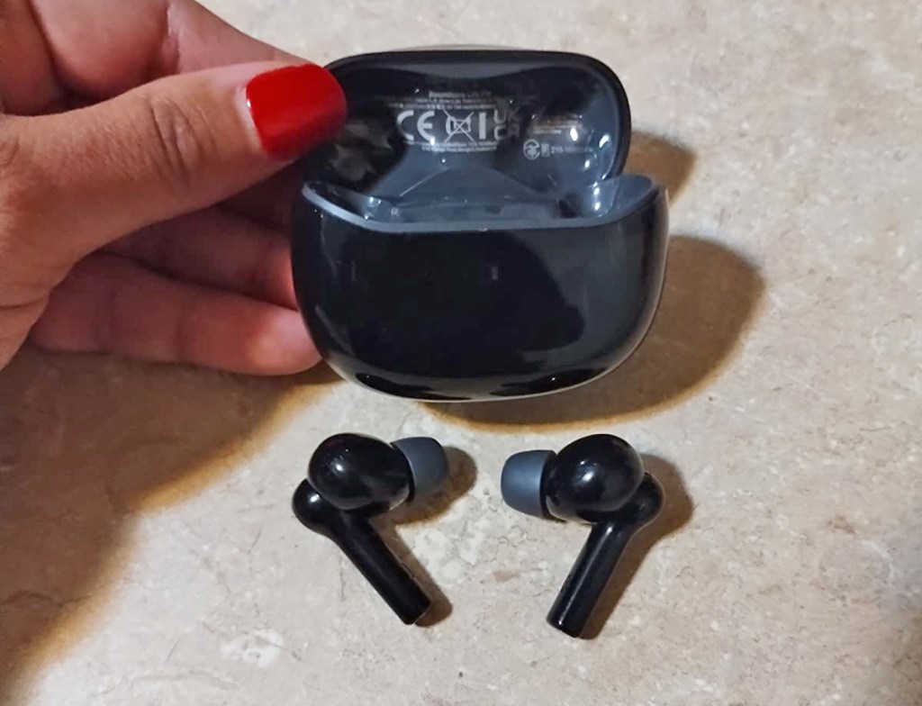 hand holding black earbuds charging case