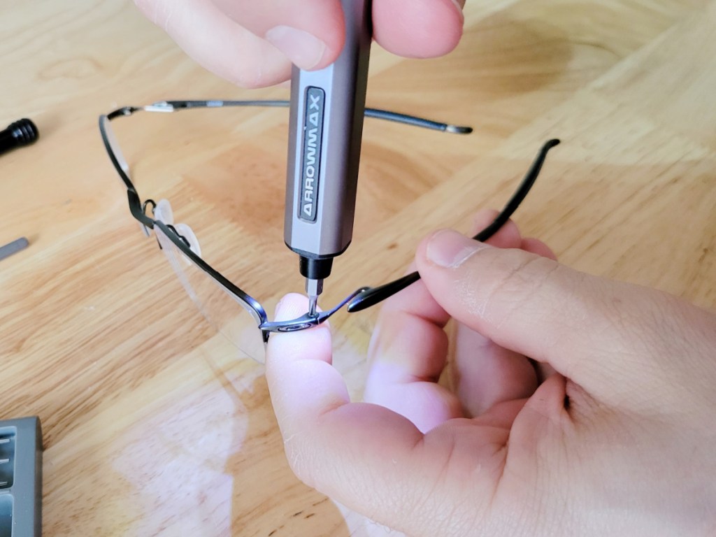 Hand using an electric screwdriver on a pair of glasses