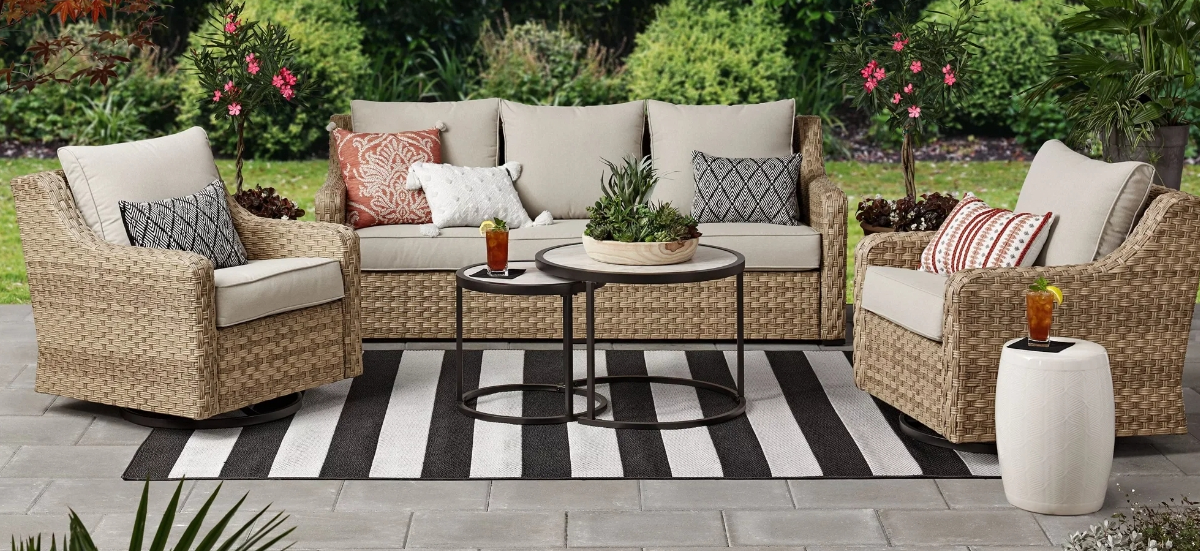 Wicker patio set sitting outside with a striped rug underneath it.