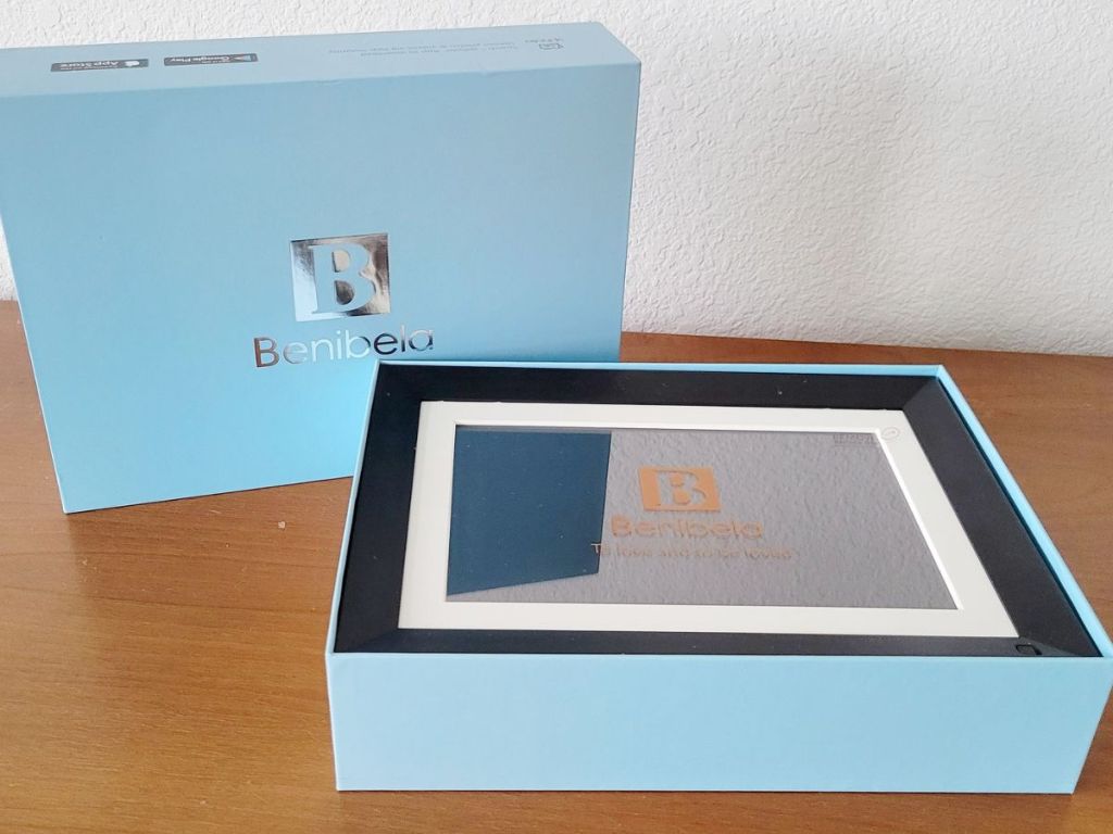 Benibela Digital Frame in its just opened box with the lid displaying the company logo standing up next to the bottom portion of the box