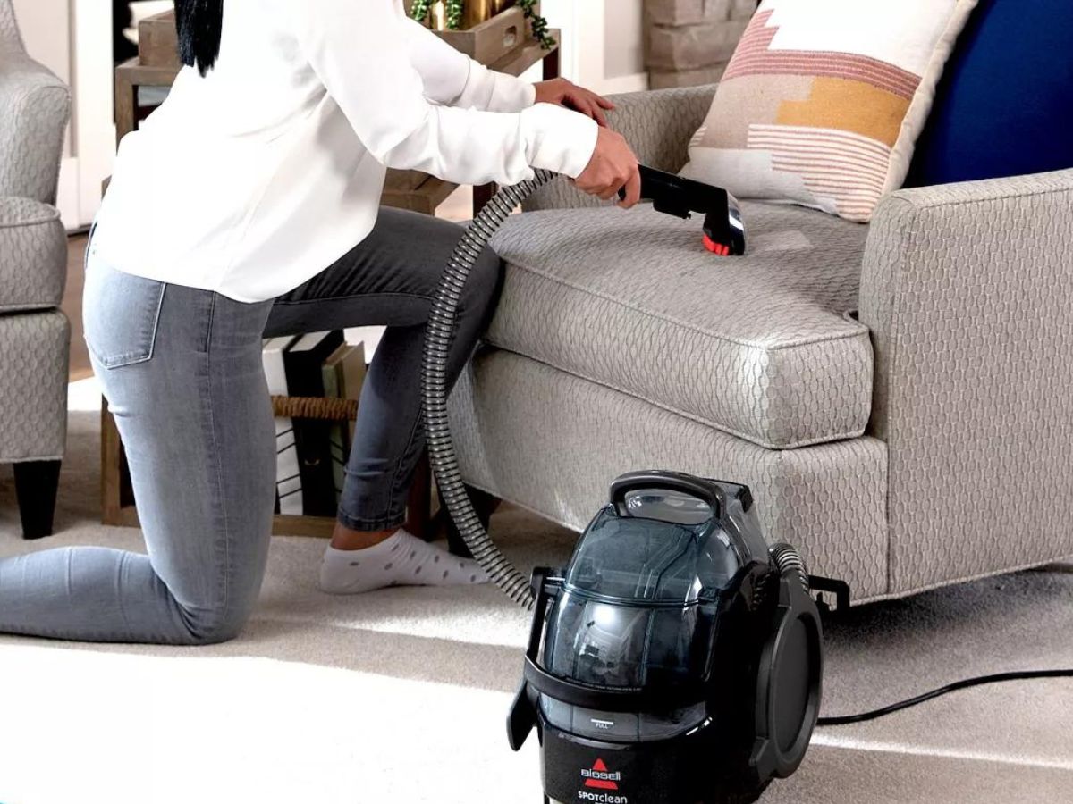 woman cleaning sofa with Bissell SpotClean Pro Portable Deep Cleaner