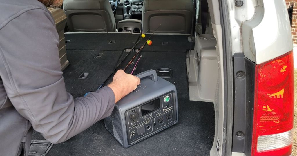 man putting Bluetti Portable Power Station in back of vehicle