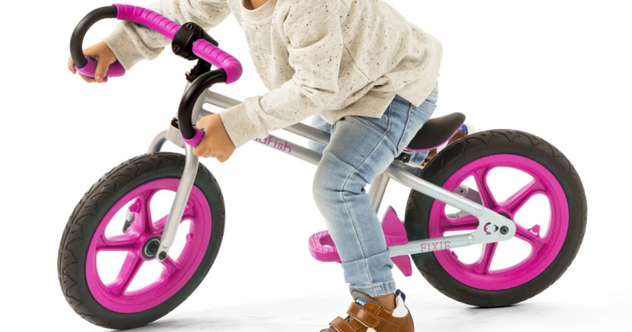 kid on a pink and silver balance bike