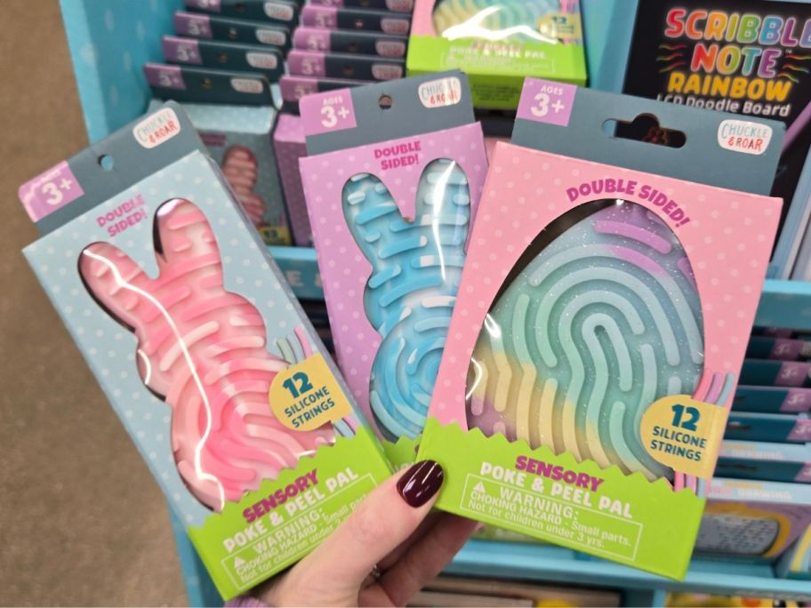 three Chuckle & Roar Poke & Peel Pads in hand in store