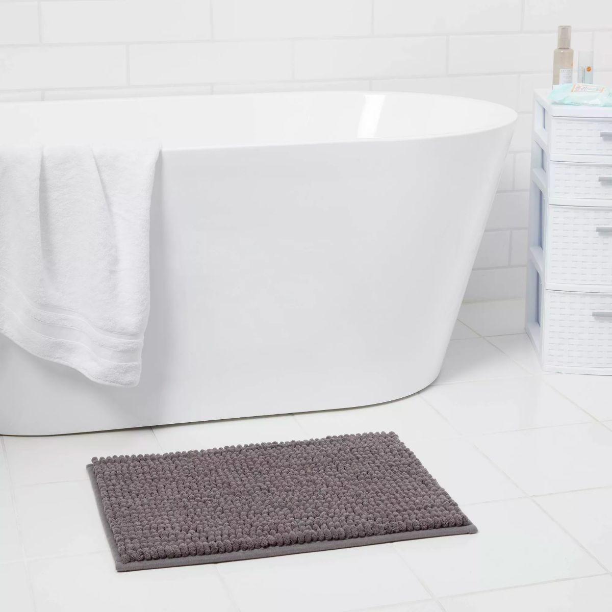 A gray Chunky Chenille Memory Foam Bath Rug in front of a soaking tub