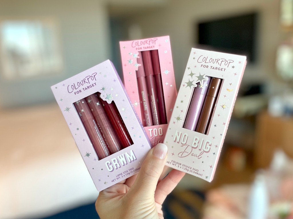 holding 3 boxed lip product gift sets