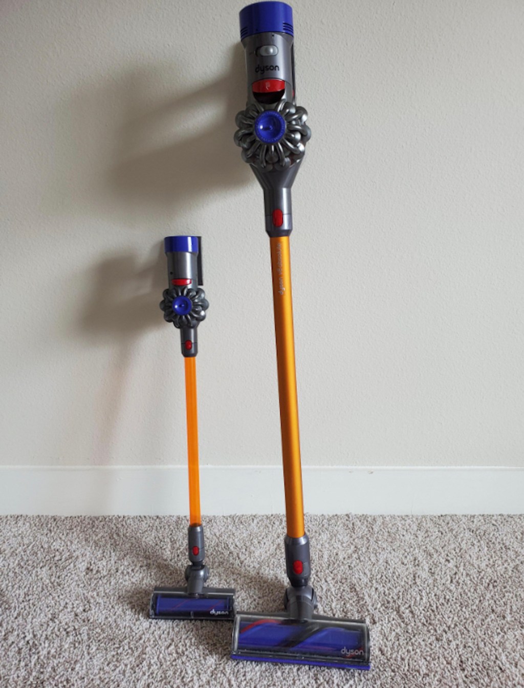 toy and adult size dyson vacuum cleaners leaning on wall
