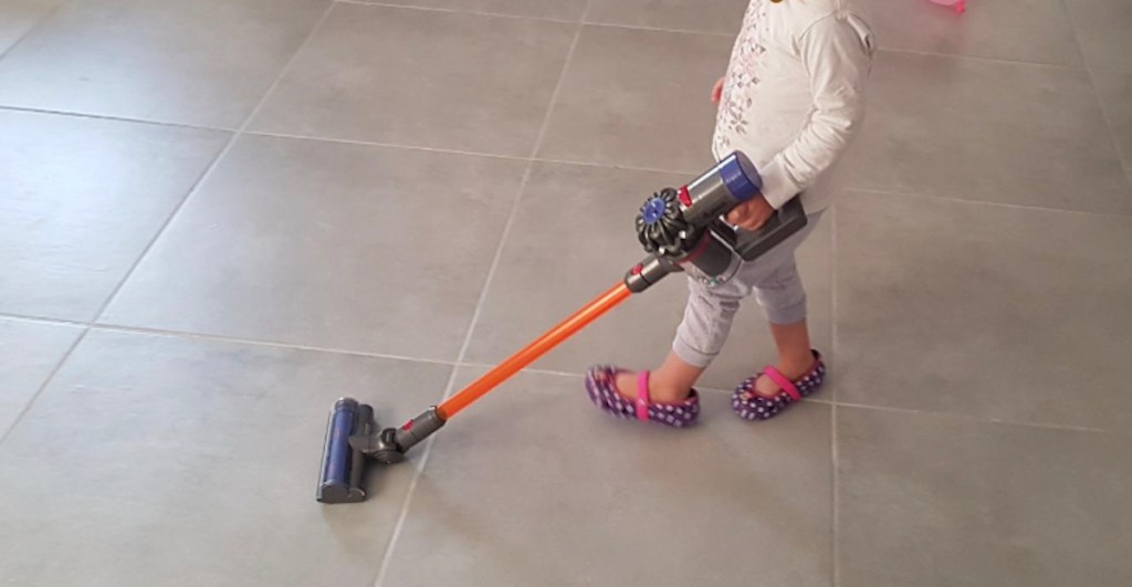 child pushing dyson vacuum on tile floor