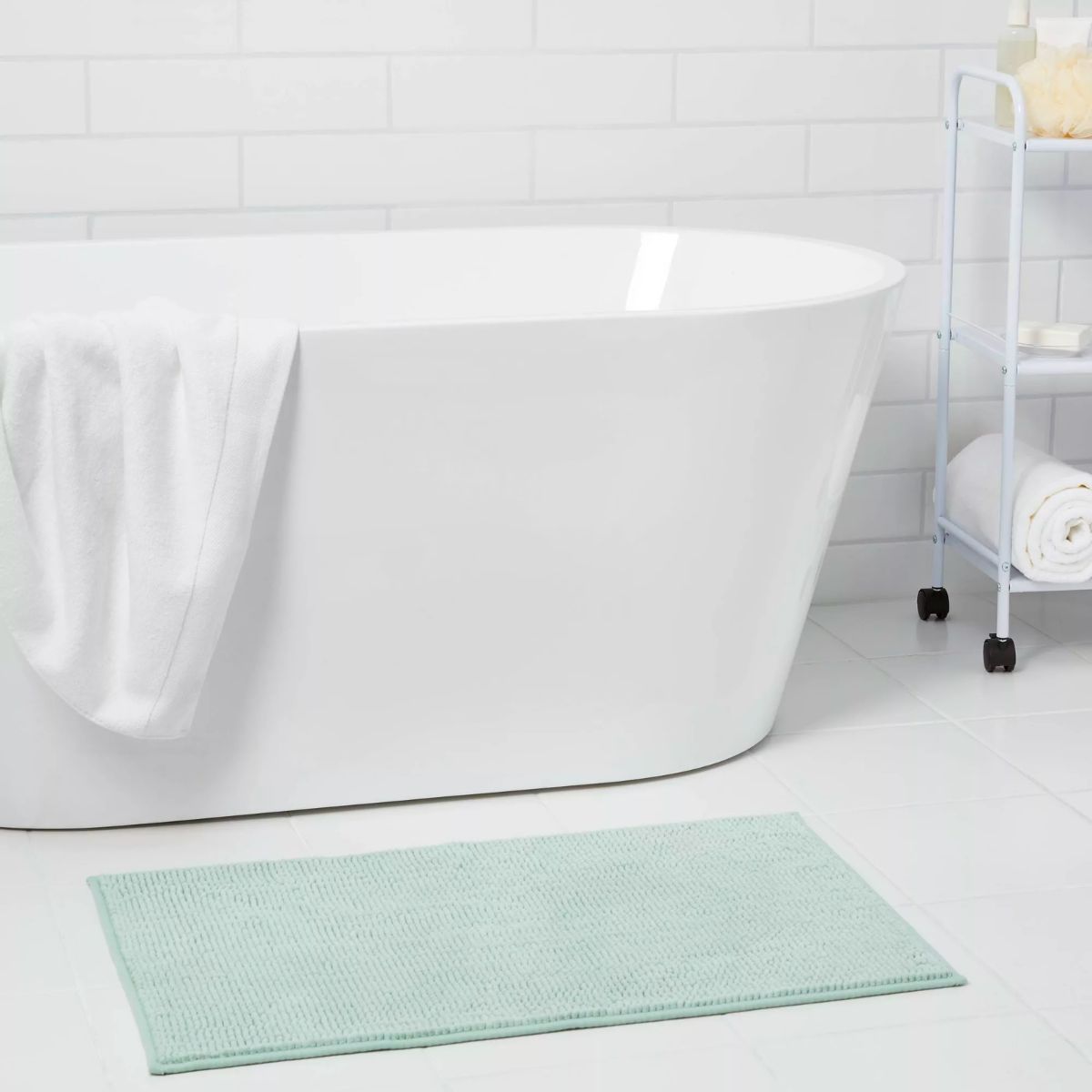 Everyday Chenille Bath Rug in mint in front of a soaking tub.
