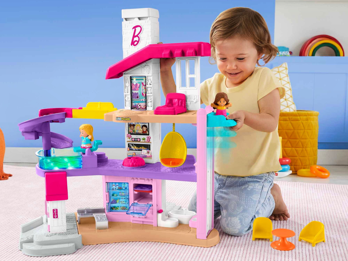 little girls on the floor okaying with a Fisher-Price Little People Barbie Little Dreamhouse Interactive Playset