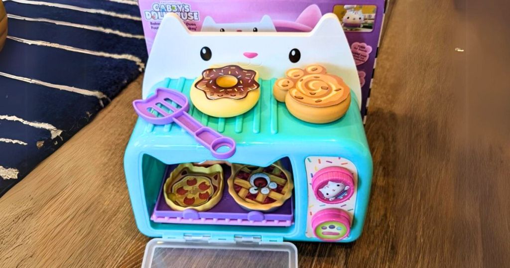 child's play baking oven with play food and utensil sitting on floor