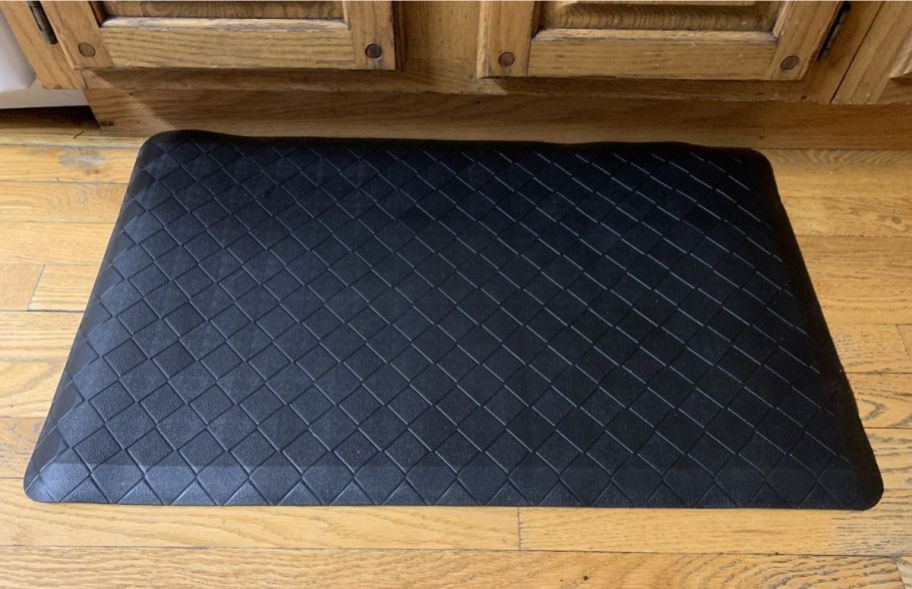 a black ergonomic floor mat in front of a set of kitchen cabinets
