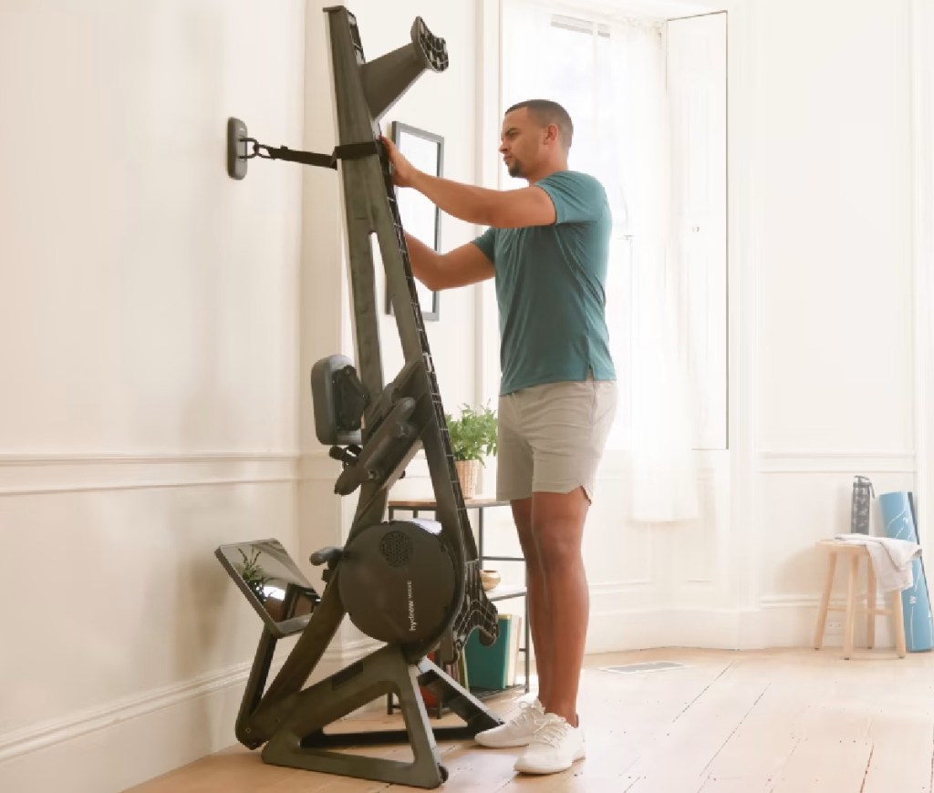 man leaning workout machine against wall 