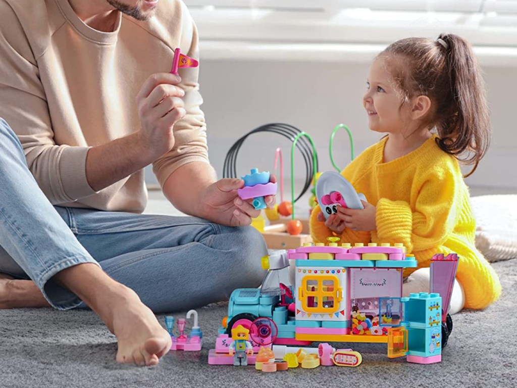 woman and girl sitting with a buildable playset toy