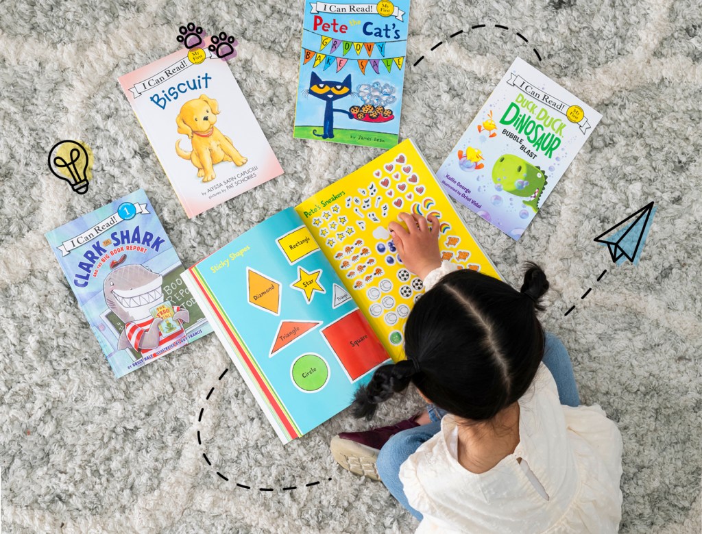 little girl reading book with other I Can Read books sprawled out on floor