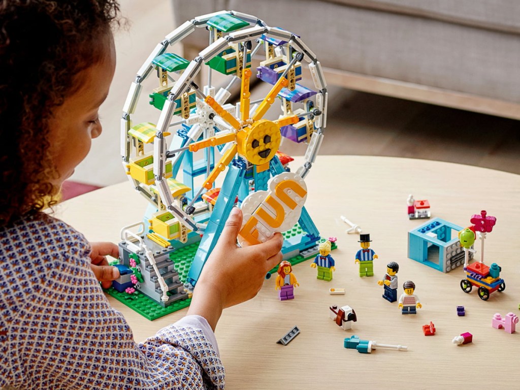 little girl playing with a LEGO Creator Ferris Wheel set