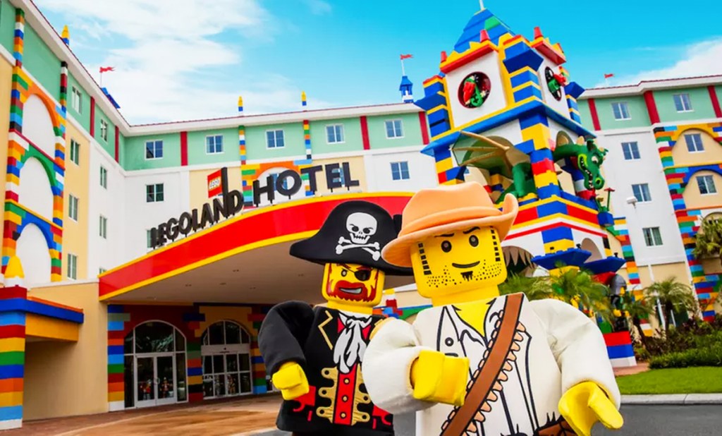 two lego characters in front of lego themed hotel