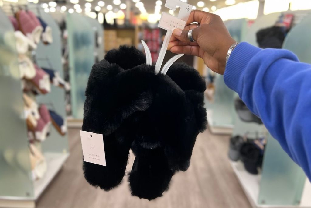 a woman's hand holding a pair of Lauren Conrad Womens Faux Fur Slippers in black