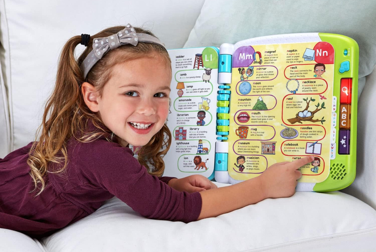 A girl reading a LeapFrog Learn with me from A to Z book