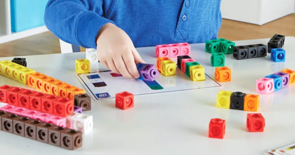 boy playing with set of mathlink cubes on table
