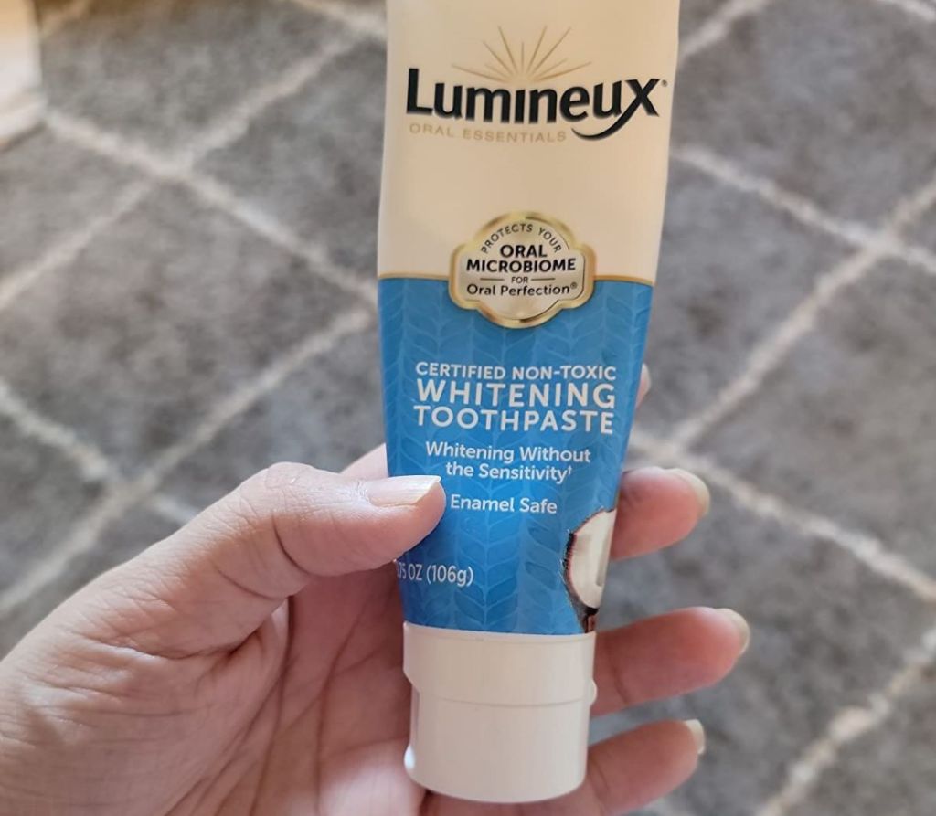 Hand holding a tube of Lumineux Toothpaste
