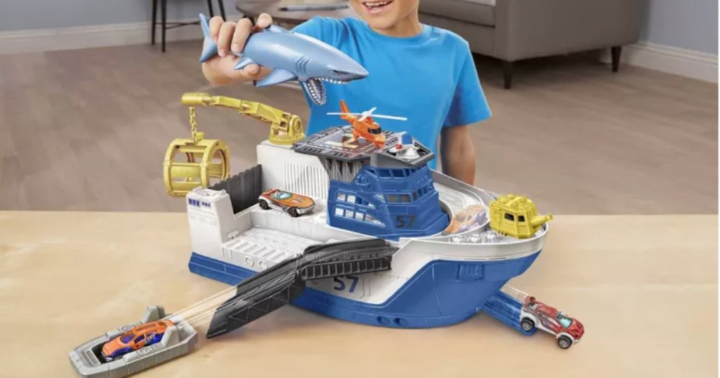child playing with toy ship and shark 
