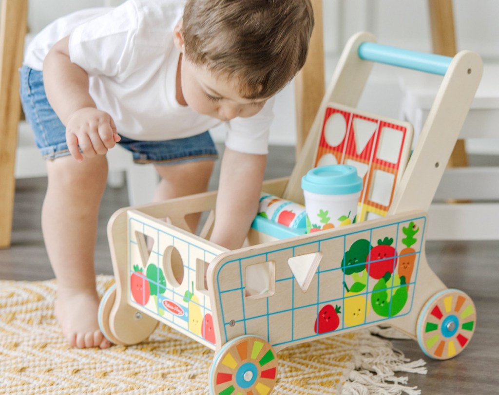 toddler playing with a Melissa and Doug Wooden Shape Sorting Grocery Cart