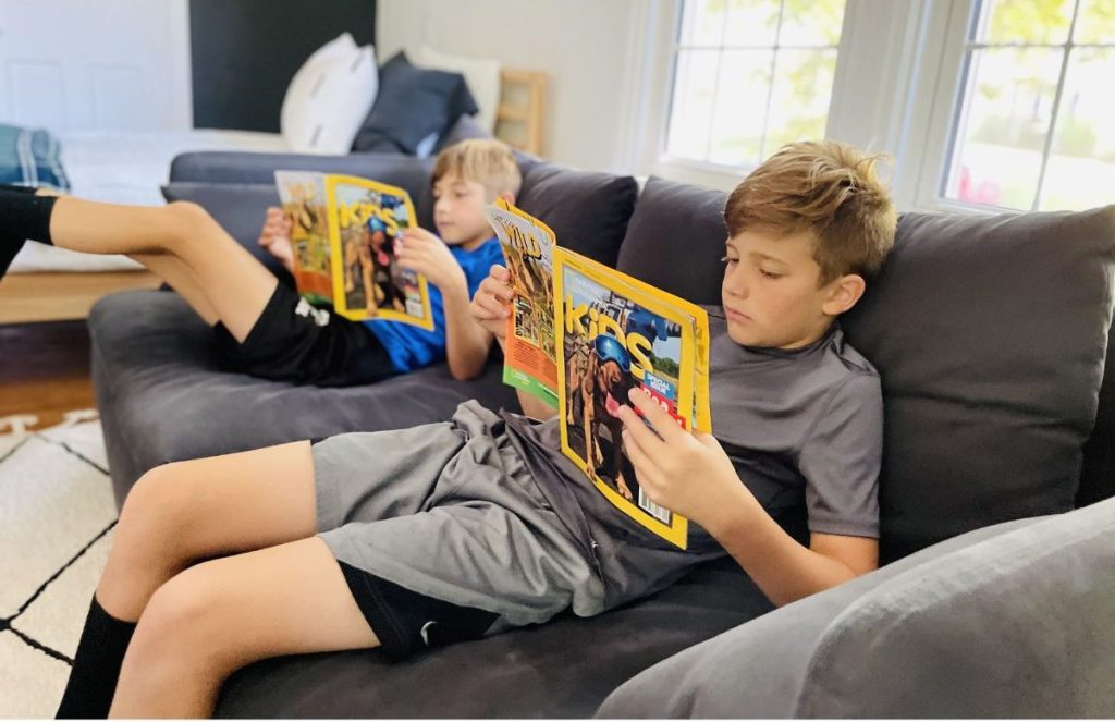 2 boys sitting on couch reading National Geogrpahic kids magazines